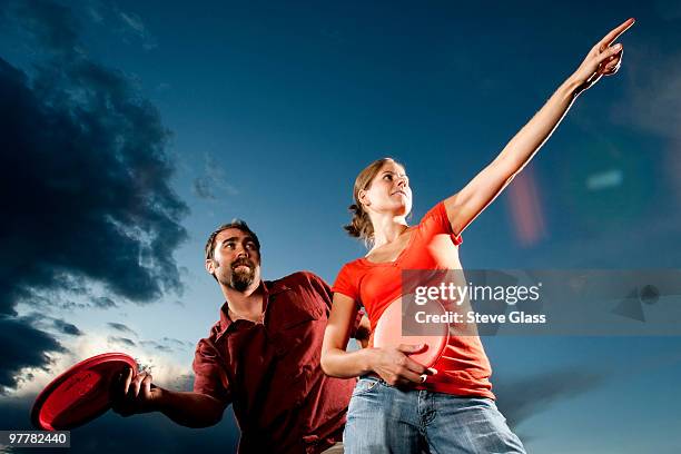 a man and woman pose while playing disk golf. - disc golf stock-fotos und bilder