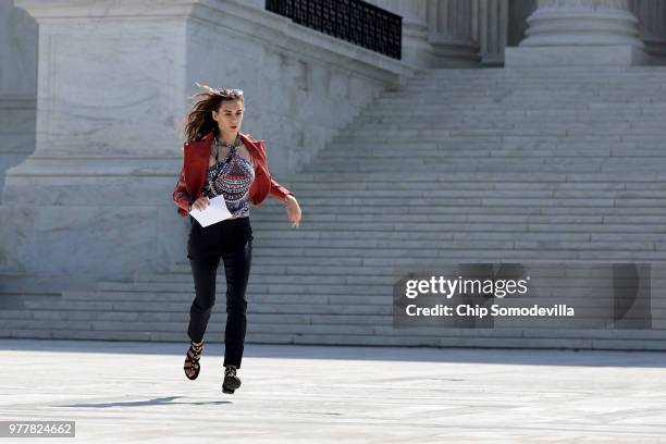 Employee Grace Williams runs across the U.S. Supreme Court plaza carrying an opinion to a news correspondent as the court handed down decisions June...