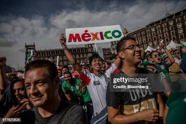 Soccer fans hold signs and shout slogans while watching a monitor broadcasting the Group F opening match of the FIFA World Cup between Mexico and...