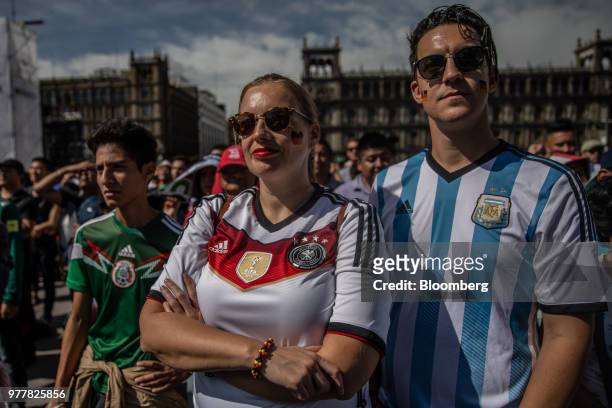 Soccer fans wear the jerseys of the German and Argentina national soccer teams while watching a monitor broadcasting the Group F opening match of the...