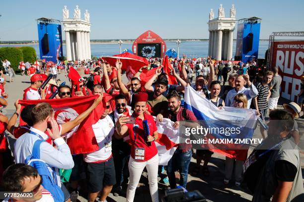 Tunisian and English fans pose for a selfie with a Russian TV anchor as they wait at the official FIFA Fan Fest in Volgograd before the Russia 2018...