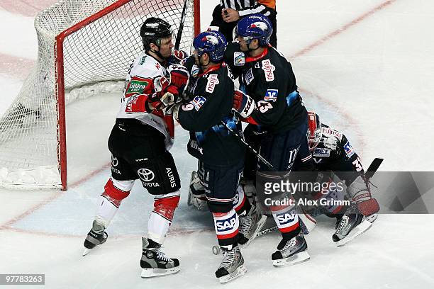 Christoph Melischko of Koeln fights with Mario Scalzo and Dan McGillis of Mannheim during the DEL match between Adler Mannheim and Koelner Haie at...