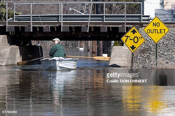 Local resident Ray Breimer paddles a rowboat on a street filled with floodewaters from the Passaic River on March 16, 2010 in Little Falls, New...