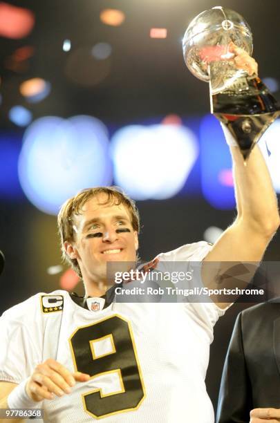 Drew Brees of the New Orleans Saints holds up the Vince Lombardi Trophy on the podium after defeating the Indianapolis Colts in Super Bowl XLIV on...