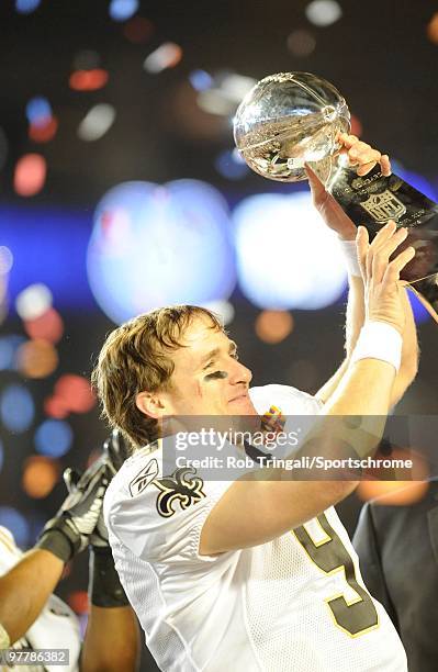 Drew Brees of the New Orleans Saints holds up the Vince Lombardi Trophy on the podium after defeating the Indianapolis Colts in Super Bowl XLIV on...