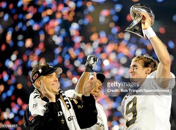 Drew Brees of the New Orleans Saints holds up the Vince Lombardi Trophy on the podium as head coach Sean Payton looks on after defeating the...