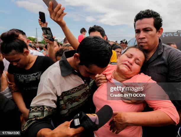 Woman faints as the coffins of her family members arrive at the "Milagro de Dios" Cemetery in Managua on June 17, 2018. - Six members of a single...