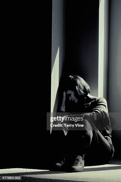 woman sitting in corner, head resting on hand (b&w) - 性暴力 個照片及圖片檔