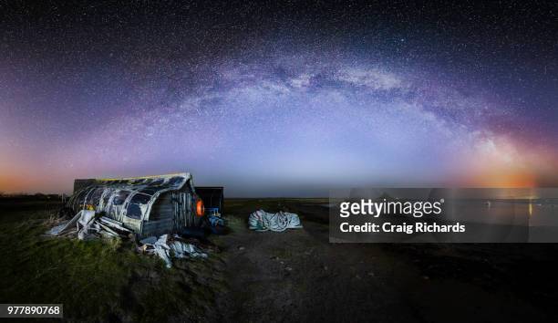 galaxy over cottage on holy island, uk - northumberland stock-fotos und bilder