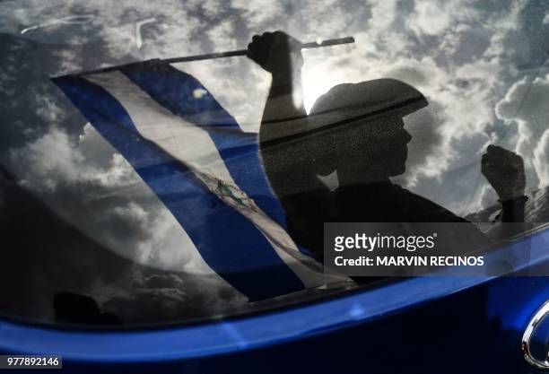 An anti-government demonstrator waves a flag while taking part in a protest in Managua, Nicaragua on June 17 demanding justice for the death of six...