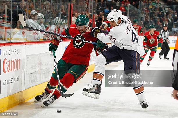 Guillaume Latendresse of the Minnesota Wild and Theo Peckham of the Edmonton Oilers skate to the puck during the game at the Xcel Energy Center on...