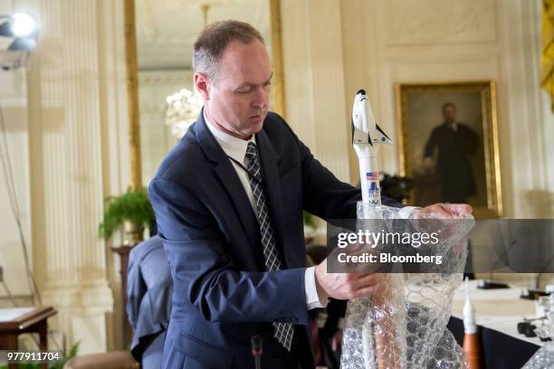 Man removes bubble wrap from a model spacecraft before a National Space Council meeting in the East Room of the White House in Washington, D.C., on...