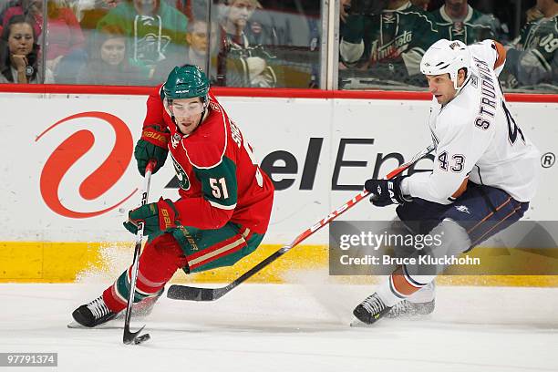 James Sheppard of the Minnesota Wild skates with the puck while Jason Strudwick of the Edmonton Oilers defends during the game at the Xcel Energy...