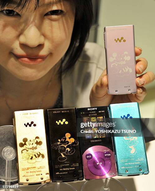 Japanese Sony employee poses with the company's digital audio player "Walkman S-series", engraved with designs of Disney characters Mickey and Minnie...
