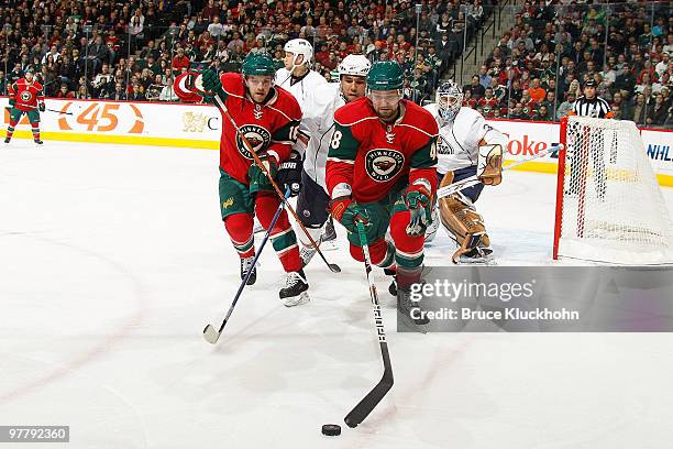 Andrew Ebbett and Guillaume Latendresse of the Minnesota Wild skate to the puck along with Theo Peckham of the Edmonton Oilers during the game at the...