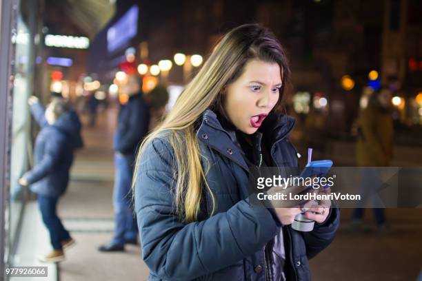 girl downtown at night using phone - mobile bad news stock pictures, royalty-free photos & images