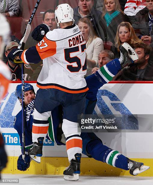 Tanner Glass of the Vancouver Canucks is checked off his feet by Blake Comeau of the New York Islanders during their game at General Motors Place on...