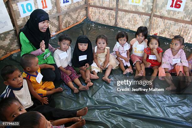 Woman talks to children gathered together in an evacuation camp on March 17, 2010 in Datu Anggal Midtimbang, Maguindanao Province, Philippines....