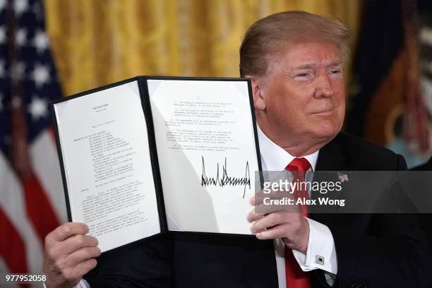 President Donald Trump holds up an executive order that he signed during a meeting of the National Space Council at the East Room of the White House...