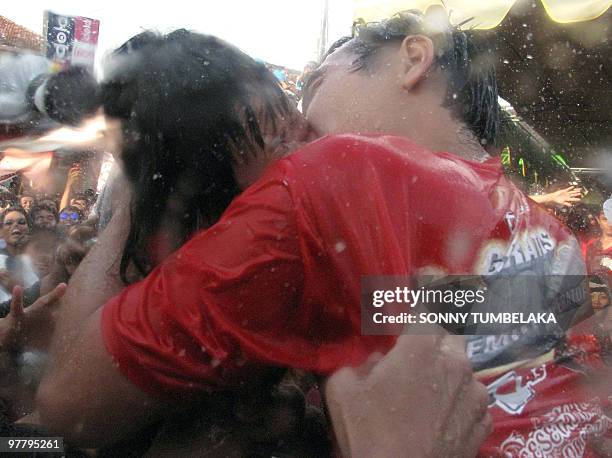 Balinese couple kiss while the crowd pours water over them during the traditional kissing festival called "Omed-Omedan" in Denpasar on the resort...