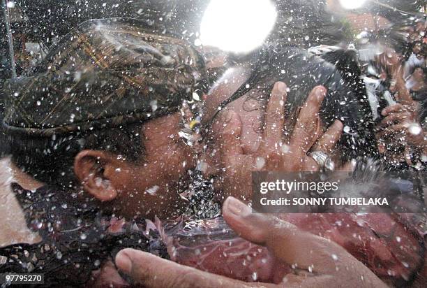 Balinese couple kiss while the crowd pours water over them during the traditional kissing festival called "Omed-Omedan" in Denpasar on the resort...