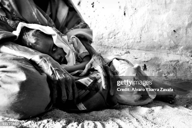 Sick child being cradeled byt one of their parents, in Iriba, Chad.