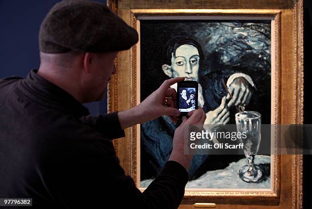Man uses his mobile phone to photograph a 1903 painting by Pablo Picasso entitled 'Portrait of Angel Fernandez de Soto ' in Christie's auction house...