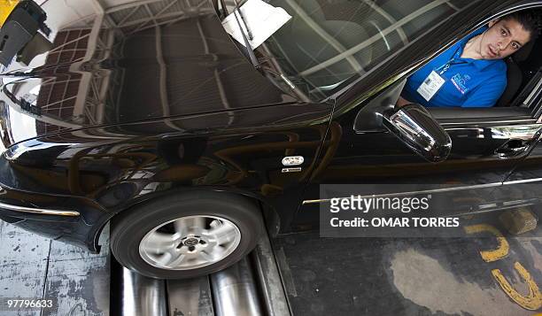 An operator of one of a center of environmental control in Mexico City checks the tuning of a car's engine on March 9, 2010 for the emission of ozone...