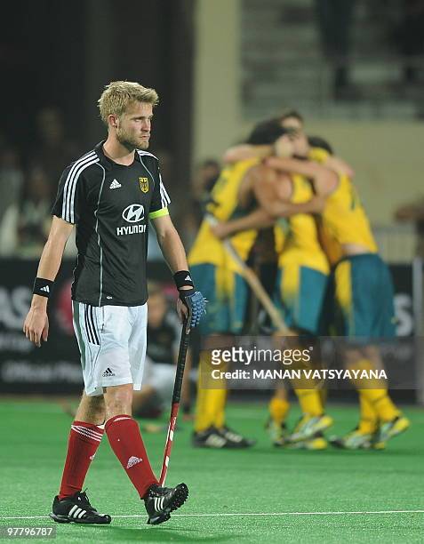 Germany hockey captain Maximilian Muller looks dejected as Australian hockey players celebrate after winning the World Cup 2010 Final match against...