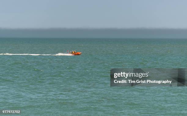 inflatable orange rnli life boat at full speed - rubber dingy stock pictures, royalty-free photos & images