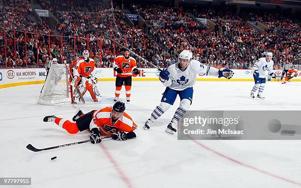 Jeff Carter of the Philadelphia Flyers is tripped up by Luca Caputi of the Toronto Maple Leafs on March 7, 2010 at Wachovia Center in Philadelphia,...