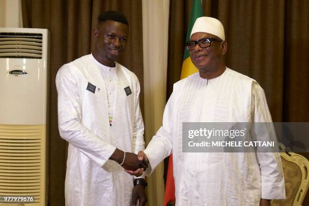 Mali's President Ibrahim Boubacar Keita shakes hand with Malian immigrant in France turned hero, Mamoudou Gassama during their meeting on June 18,...