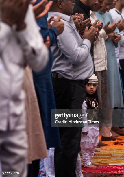 Child look on as Muslims take part in prayers outside the Bandra station on the occasion of Eid al Fitr on June 16, 2018 in Mumbai, India. The...