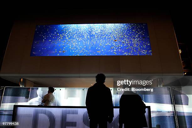 Visitors look at a giant aquarium at the Breitling stand at the Baselworld watch fair in Basel, Switzerland, on Wednesday, March 17, 2010. The...