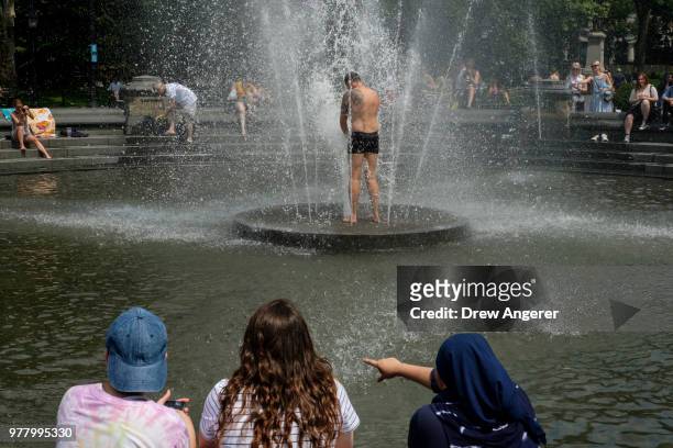 Man cools off in the fountain at Washington Square Park, June 18, 2018 in New York City. Temperatures are forecasted to hit the low 90s on Monday in...