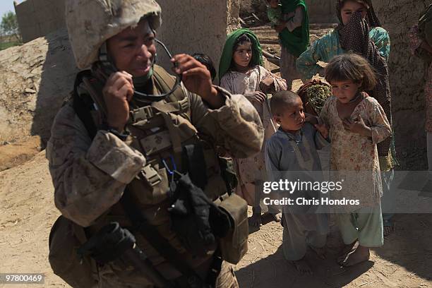 Marine Cpl. Ramona Brown of Fayetteville, North Carolina puts on her sunglasses as Pashtun children look on March 11, 2010 in a hamlet near Khan...