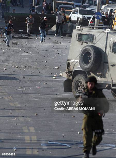 Palestinian youths hurl stones at Israeli soldiers during clashes on March 17, 2010 in the West Bank refugee camp of Qalandia. Tensions over...