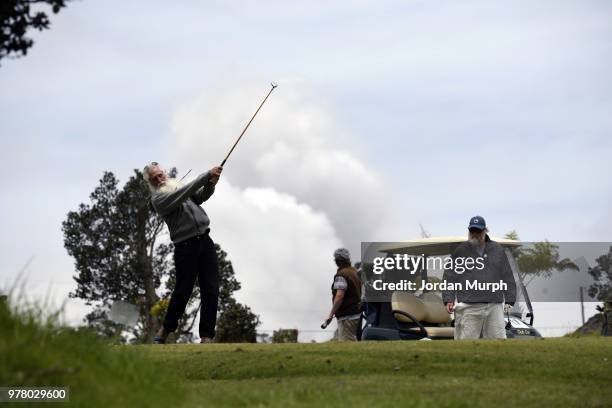 Golfers in action on the Volcano Golf Course next to the Halema'uma'u crater with ash clouds from the erupting Kilauea volcano in the background. The...