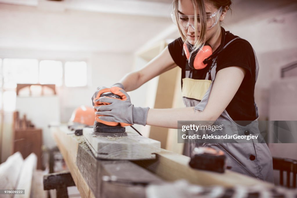 Female Carpenter Sanding Wood Block