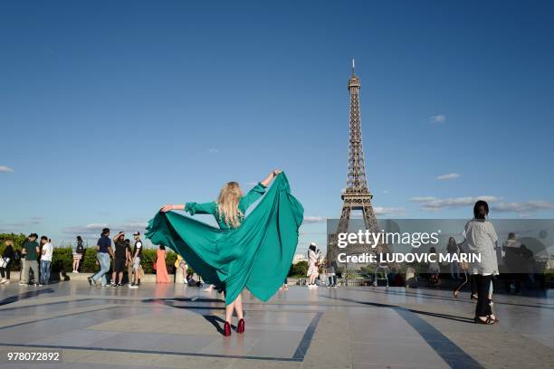 Russian woman, wearing a green dress, poses for souvenir pictures in front of the Eiffel Tower, on the Trocadero esplanade, also called Square of...