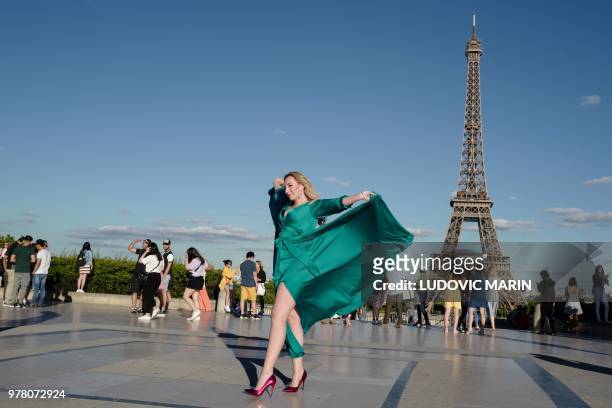 Russian woman, wearing a green dress, poses for souvenir pictures in front of the Eiffel Tower, on the Trocadero esplanade, also called Square of...