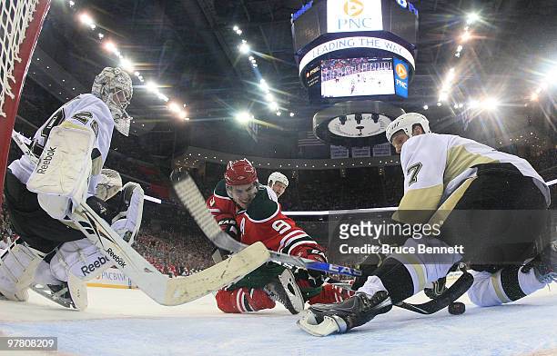 Zach Parise of the New Jersey Devils scores past Marc-Andre Fleury and Mark Eaton of the Pittsburgh Penguins at the Prudential Center on March 17,...