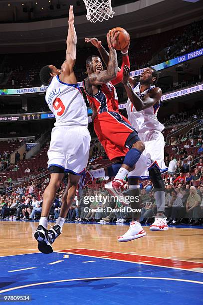 Terrence Williams of the New Jersey Nets shoots against Andre Iguodala and Samuel Dalembert of the Philadelphia 76ers during the game on March 17,...