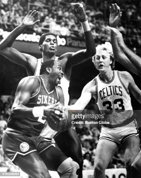 Philadelphia 76ers' Moses Malone is guarded closely by the Celtics' Robert Parish, left, and Larry Bird as he goes for a driving layup. The Boston...