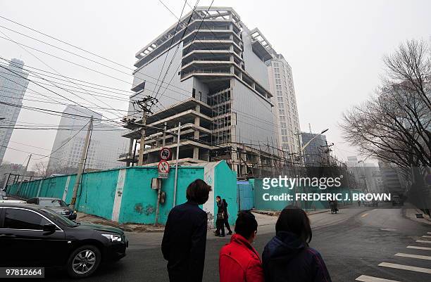 Pedestrians walk past an unfinished building in Beiijng on March 18, 2010. China will launch a nationwide campaign to crack down on the real estate...