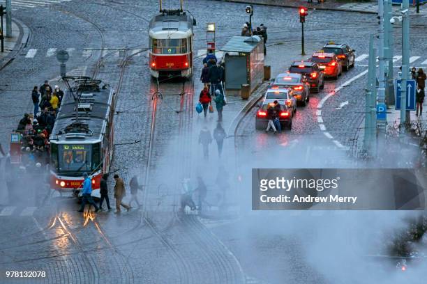 prague street scene with trams, traffic and pedestrians on cobblestone road and large smoke cloud - czech culture stock pictures, royalty-free photos & images