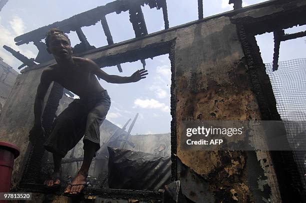 Resident inspects a gutted house after a fire raced through a squatter area in Manila on March 18, 2010. Around 200 hundred houses were burned to the...