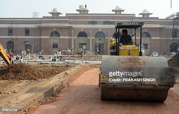 In this picture taken on December 6 Indian labourers use a roller at the Dhyan Chand National Stadium as construction works for the Commonwealth...