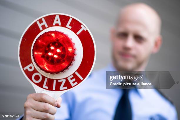 April 2018, Germany, Moenchengladbach: A police officer holds up a police stop sign reading 'Halt Polizei' during a press event. Photo: Marius...