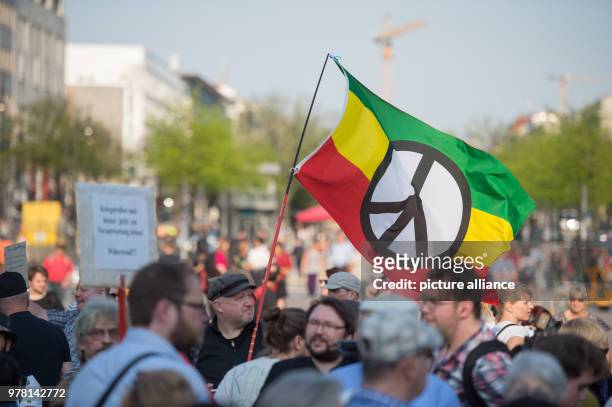 April 2018, Germany, Berlin: Protestors wave a peace flag at the rally 'Nein zum Krieg' of The Left party. On 14 April, the USA, Great Britain and...